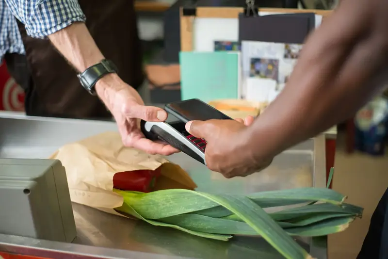 A customer paying with a phone at a shop counter