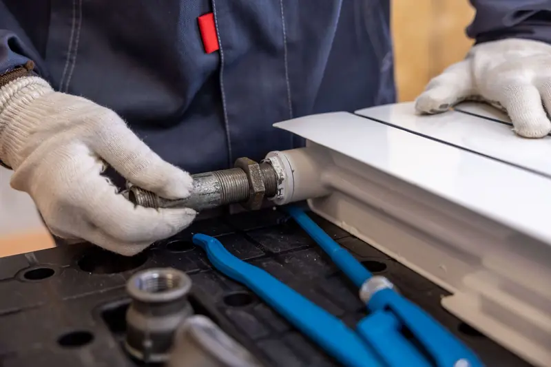 Gloved hands fitting a pipe to a radiator