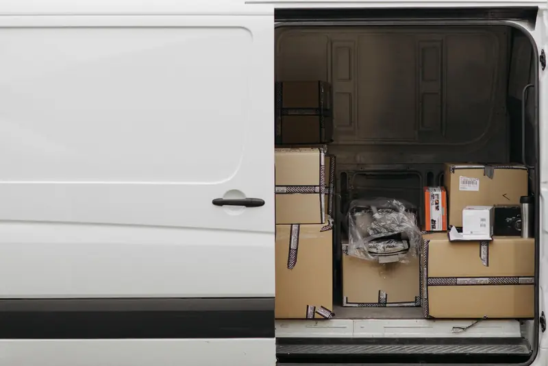 The open side door of a white van loaded with boxes